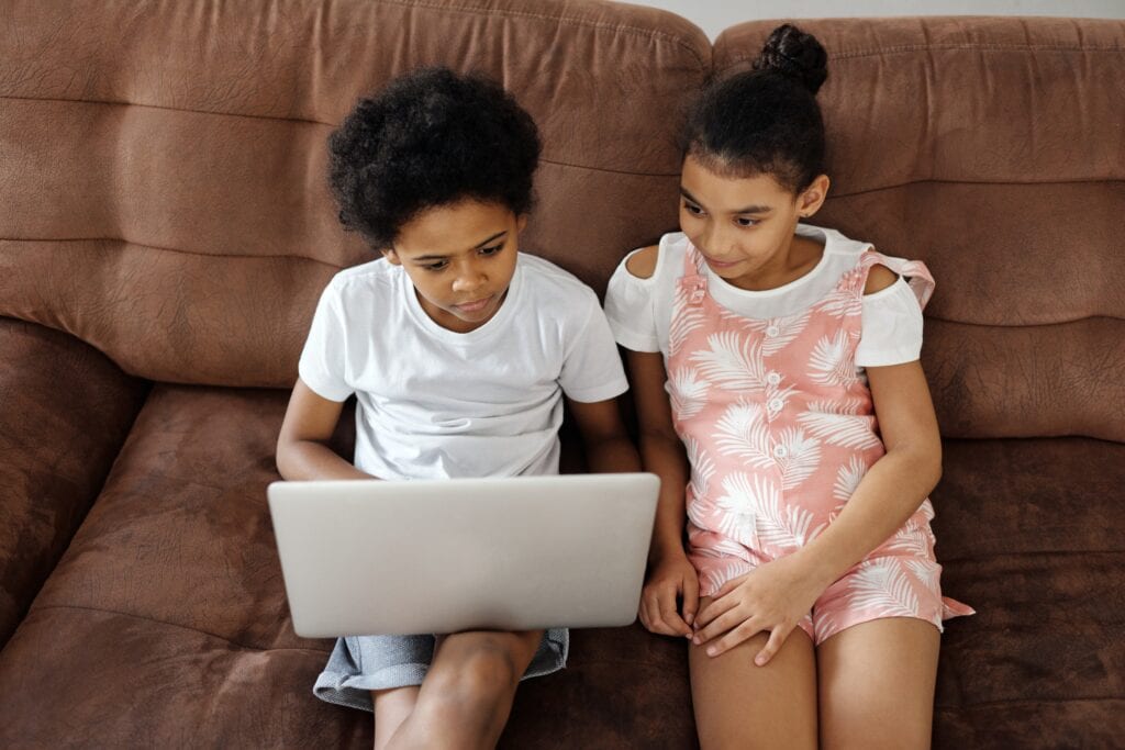 two kids looking at a laptop screen together learning science at home